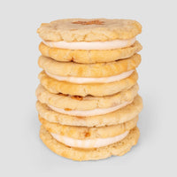 A stack of six $165 JRC Gift Bag sandwich cookies by Jenna Rae Cakes, with creamy filling between two golden, crumbly cookies, set against a plain light gray background.