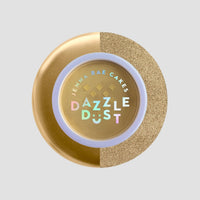A round container of Jenna Rae Cakes Dazzle Dust Best Seller Trio features a gold lid, glittery texture on one side, and colorful holographic text, set against a plain light gray background.