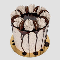 Jenna Rae Cakes’ Chocolate Oreo Cake features layers of cookies and cream, chocolate drip icing, swirls of cream, and Oreo halves, beautifully presented on a gold cake board.