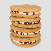 A stack of five Jenna Rae Cakes Regular Cookie Sandwiches, filled with vanilla cream and chocolate sauce, displayed against a plain light gray background.