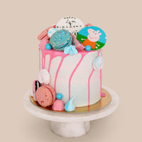 The Kids Works Cake by Jenna Rae Cakes features pink icing drips, colorful macarons, meringues, blue candies, and a Peppa Pig topper on a marble stand. A white “Happy 4th Birthday” topper completes the look against a beige background.