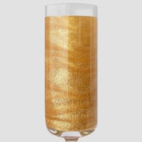 A clear champagne flute filled with golden FND TESTING - 24k Magic Edible Glitter by Jenna Rae Cakes shimmers against a plain light gray background.