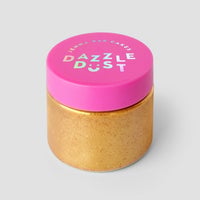 A gold jar with a bright pink lid labeled FND TESTING - 24k Magic Edible Glitter (Copy) by Jenna Rae Cakes contains edible glitter, shown against a plain gray background.