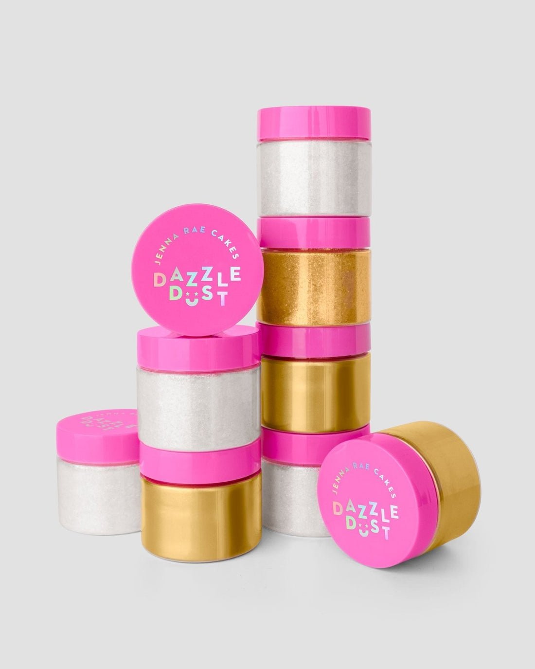 Three packages of Jenna Rae Cakes Antique Gold Edible Lustre Dust (20g each, 3 jars per pack) are stacked in uneven columns. The metallic gold jars have bright pink lids with white and blue text, against a plain light gray background.