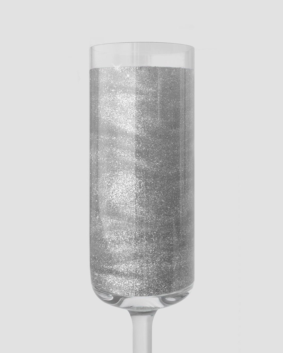 A sparkling silver liquid in a clear champagne flute showcases Jenna Rae Cakes’ Disco Ball Edible Glitter (20g, 3-pack), set against a light gray background.