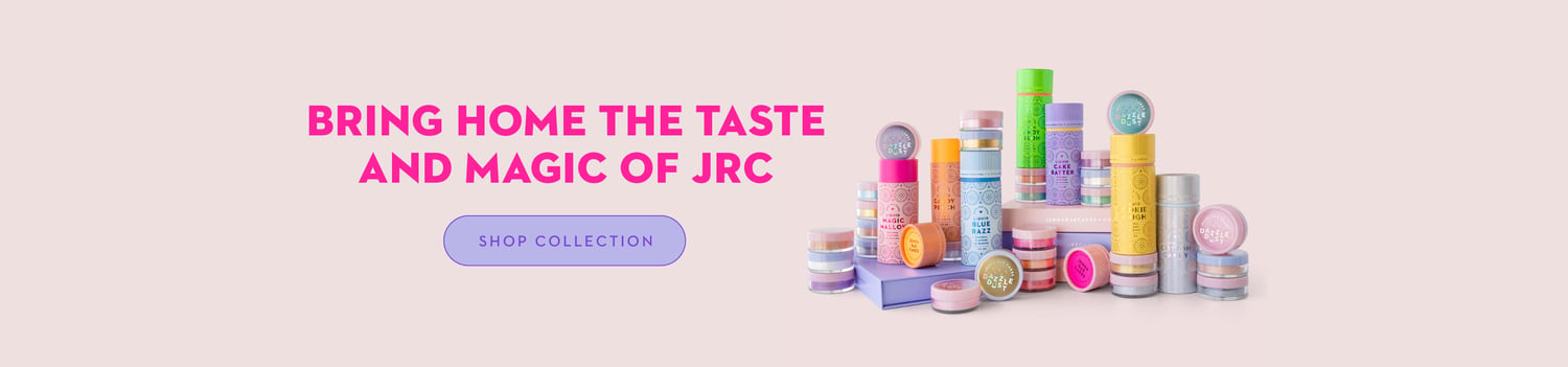 Colorful cosmetic containers and jars are arranged on a light surface with the text BRING HOME THE TASTE AND MAGIC OF JRC and a purple SHOP COLLECTION button on the left against a pink background.