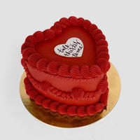 The Heart Cake by Jenna Rae Cakes is a heart-shaped red cake with decorative red frosting and a white heart on top reading talk strictly to me, presented on a round gold cake board.