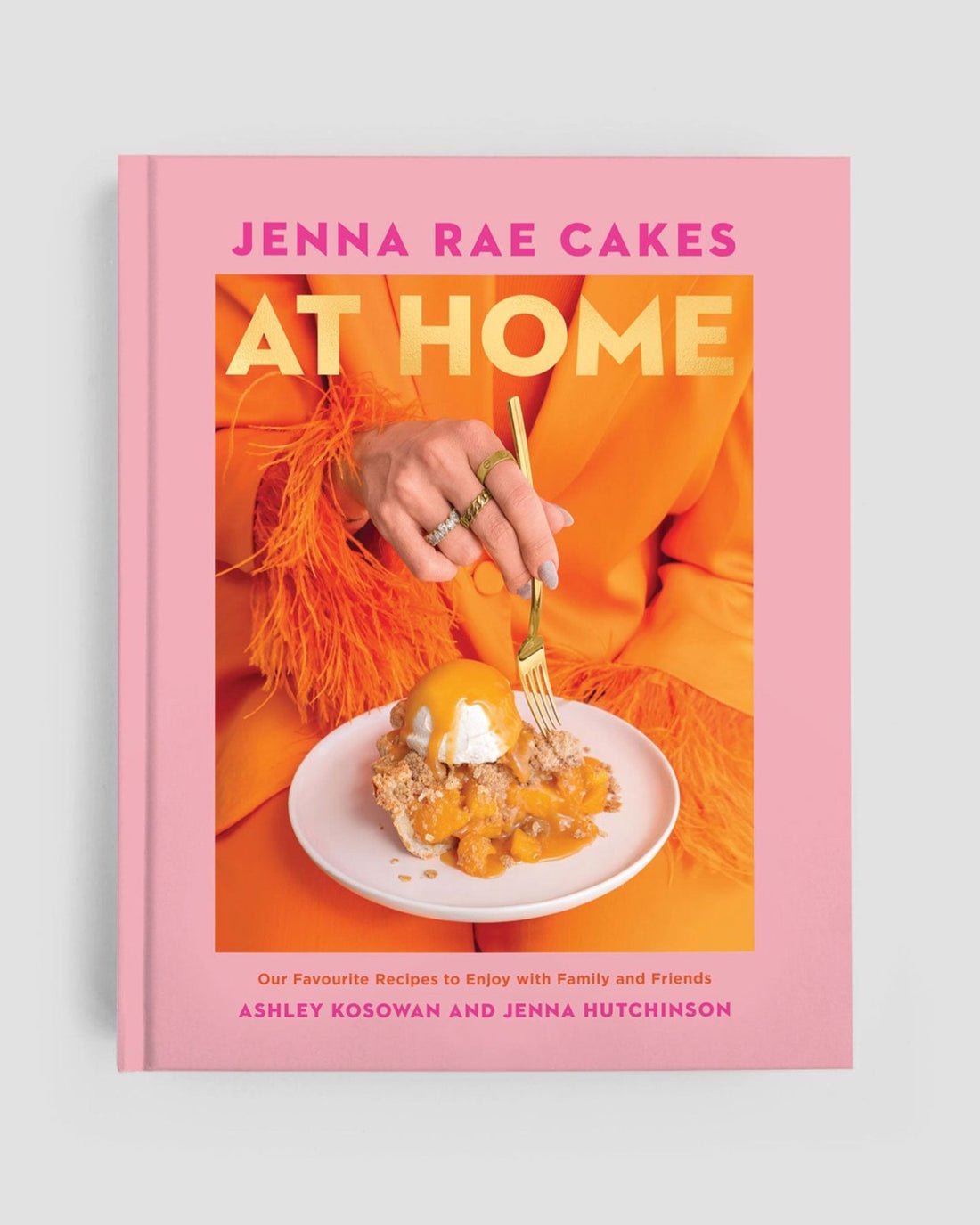 The Home Baker Bundle by Jenna Rae Cakes features a pink cookbook, Jenna Rae Cakes At Home, by Ashley Kosowan and Jenna Hutchinson, with a cover showing someone in orange cutting into a dessert topped with whipped cream and fruit.