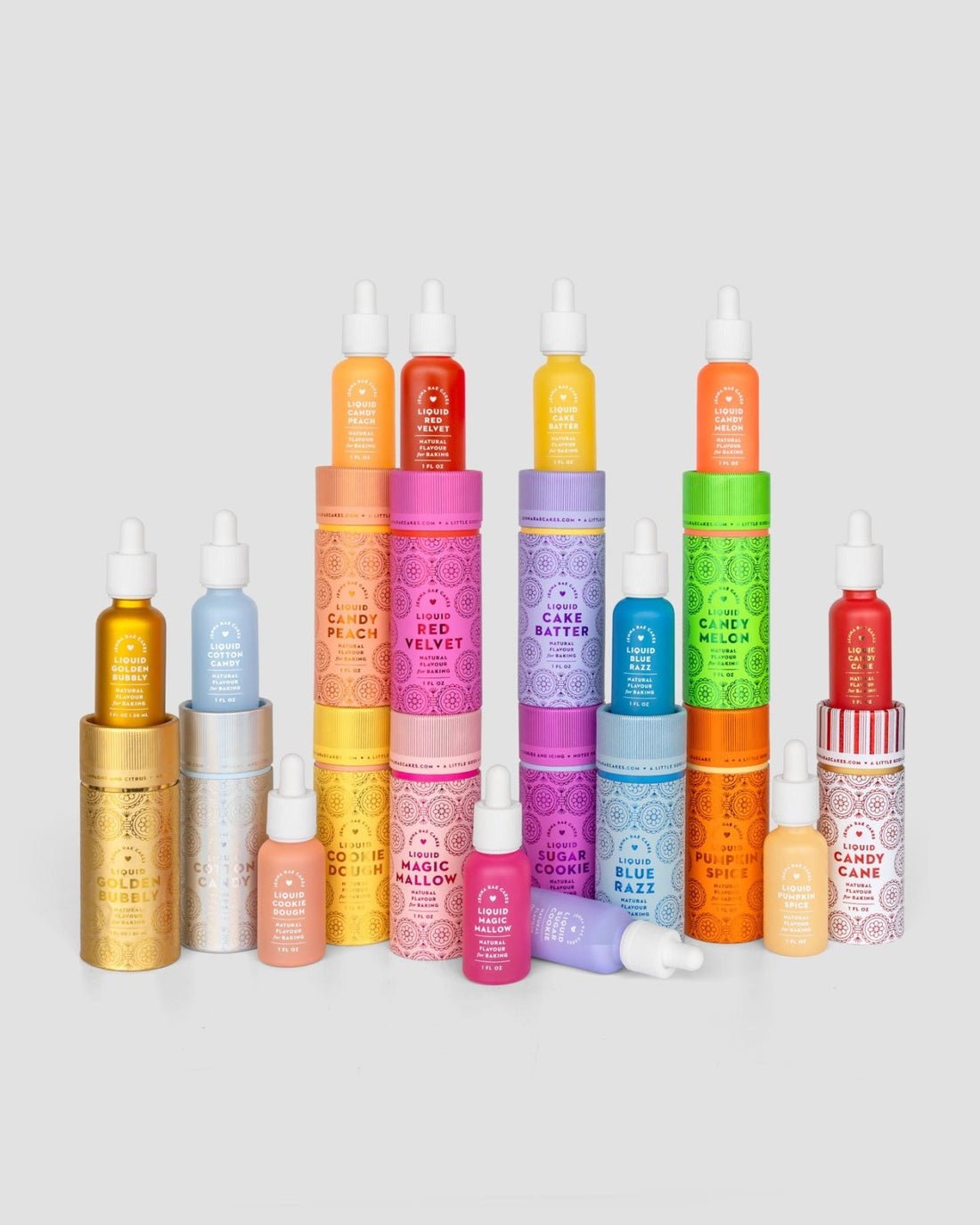 A vibrant lineup of Jenna Rae Cakes Liquid Blue Razz skincare serum bottles and matching cylindrical packaging, each with distinct colors and label designs, arranged neatly on a light gray background.