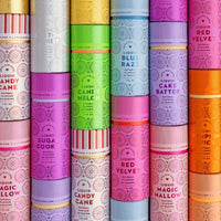 Colorful cylindrical containers from Jenna Rae Cakes, labeled Liquid Candy Cane, are stacked in rows with patterned labels.