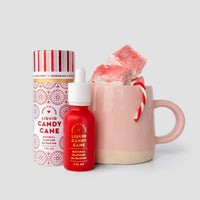 A pink mug with marshmallows, a candy cane, and Jenna Rae Cakes Liquid Candy Cane - Package of 6 with dropper and matching container are displayed against a light gray background.