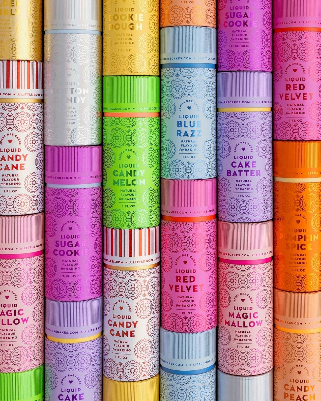 Colorful cylindrical containers of Jenna Rae Cakes Liquid Cotton Candy with bright labels, stacked in rows and featuring flavors like Cookie Dough, Blue Razz, Cake Batter, Red Velvet, Candy Cane, Pumpkin Spice, and more.