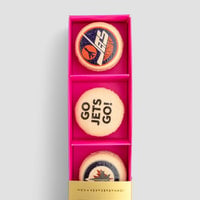 The Macaron Message Gift Box by Jenna Rae Cakes features three cookies in a pink box: one with a blue and orange logo, one with GO JETS GO!, and one with a blue, red, and white jet-themed logo.