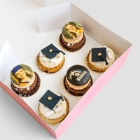 Jenna Rae Cakes Grad Works Cupcakes come in a pink box of six: three topped with edible famous painting images, and three decorated with black graduation caps and diplomas on white frosting.