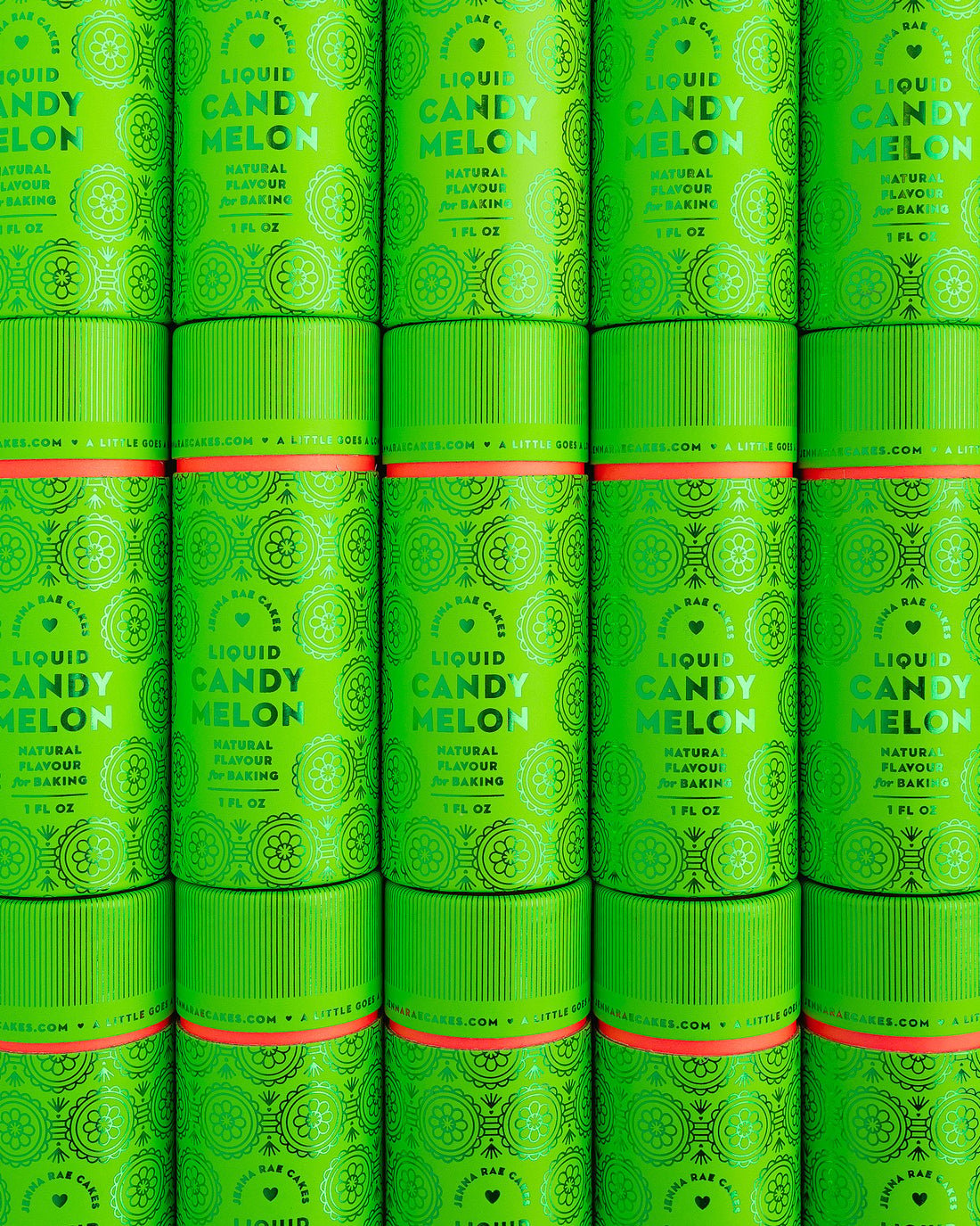 Rows of vibrant green cylindrical containers of Jenna Rae Cakes Liquid Candy Melon, adorned with decorative patterns and white text, are stacked closely together to create a visually striking, repeating display.