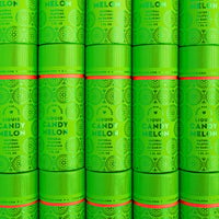 Rows of vibrant green cylindrical containers of Jenna Rae Cakes Liquid Candy Melon, adorned with decorative patterns and white text, are stacked closely together to create a visually striking, repeating display.