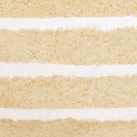 Close-up of Vanilla Cake by Jenna Rae Cakes, showing thick layers of light yellow cake and smooth white frosting with visible texture and smoothness.