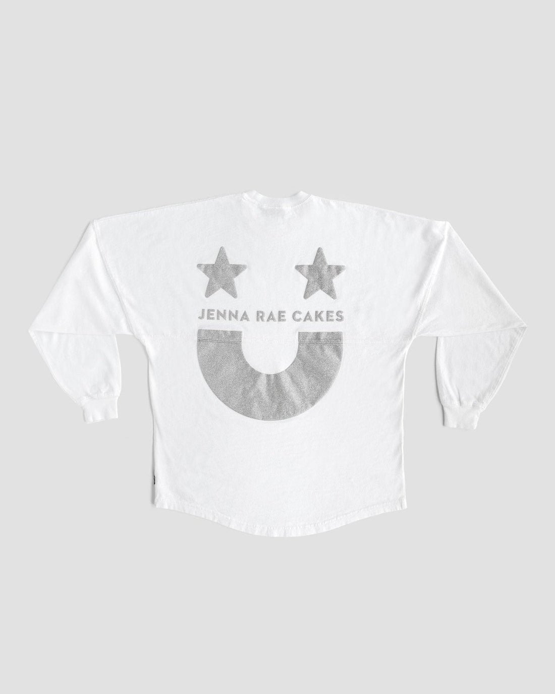 The White and Silver Spirit Jersey by Jenna Rae Cakes features two gray stars, “JENNA RAE CAKES” text, and a large gray smiley face on the back, shown on a plain gray background.