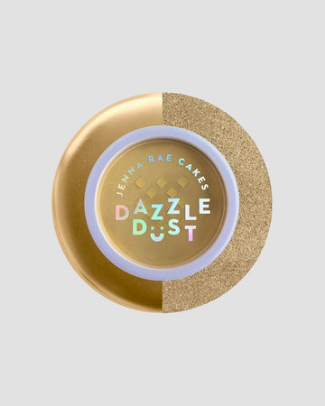 A round container of Jenna Rae Cakes Dazzle Dust Best Seller Trio features a gold lid, glittery texture on one side, and colorful holographic text, set against a plain light gray background.