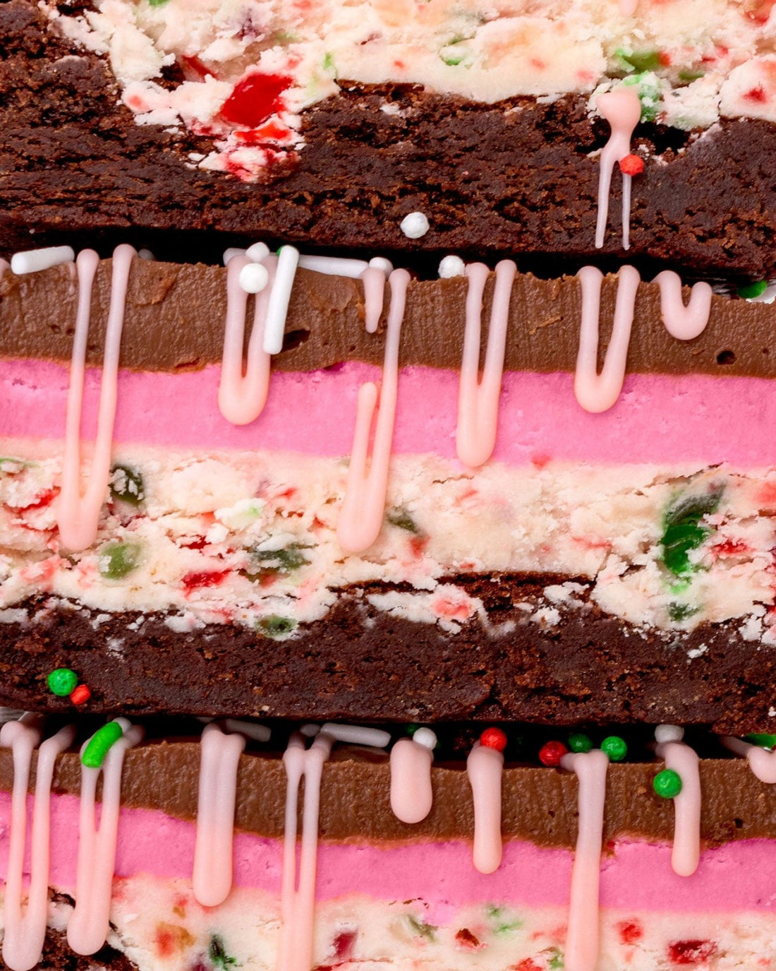 Close-up of Jenna Rae Cakes’ limited edition Candy Cane Brownie: chocolate brownie layered with pink and white cream, red and green sprinkles, and a drizzle of pink icing.