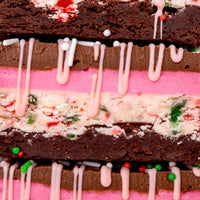 Close-up of Jenna Rae Cakes’ limited edition Candy Cane Brownie: chocolate brownie layered with pink and white cream, red and green sprinkles, and a drizzle of pink icing.