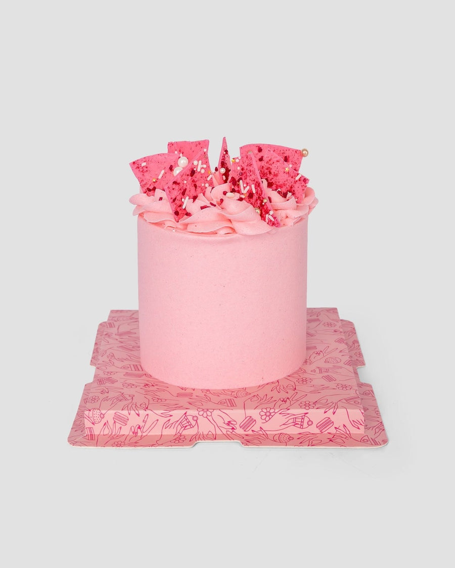 Pink cake with pink buttercream and pink chocolate shards on top.