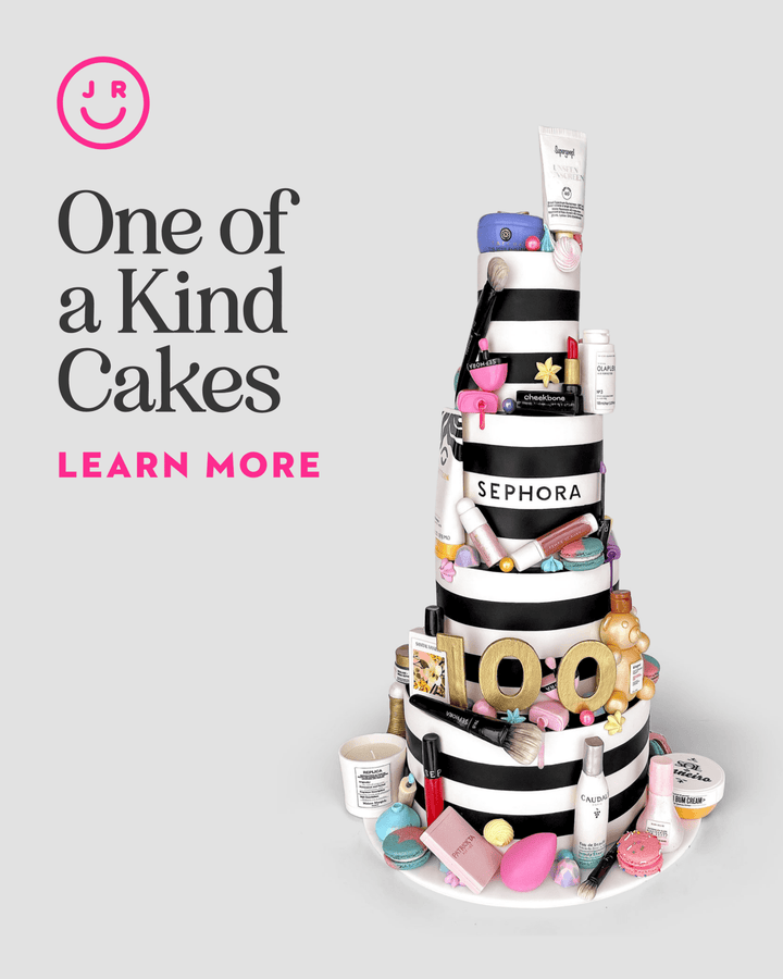 A tiered cake adorned with makeup and skincare in Sephora packaging, plus brushes and cosmetics. Text: One-of-a-Kind Cakes by Jenna Rae Cakes. Learn More. Smiling face logo in top left corner.