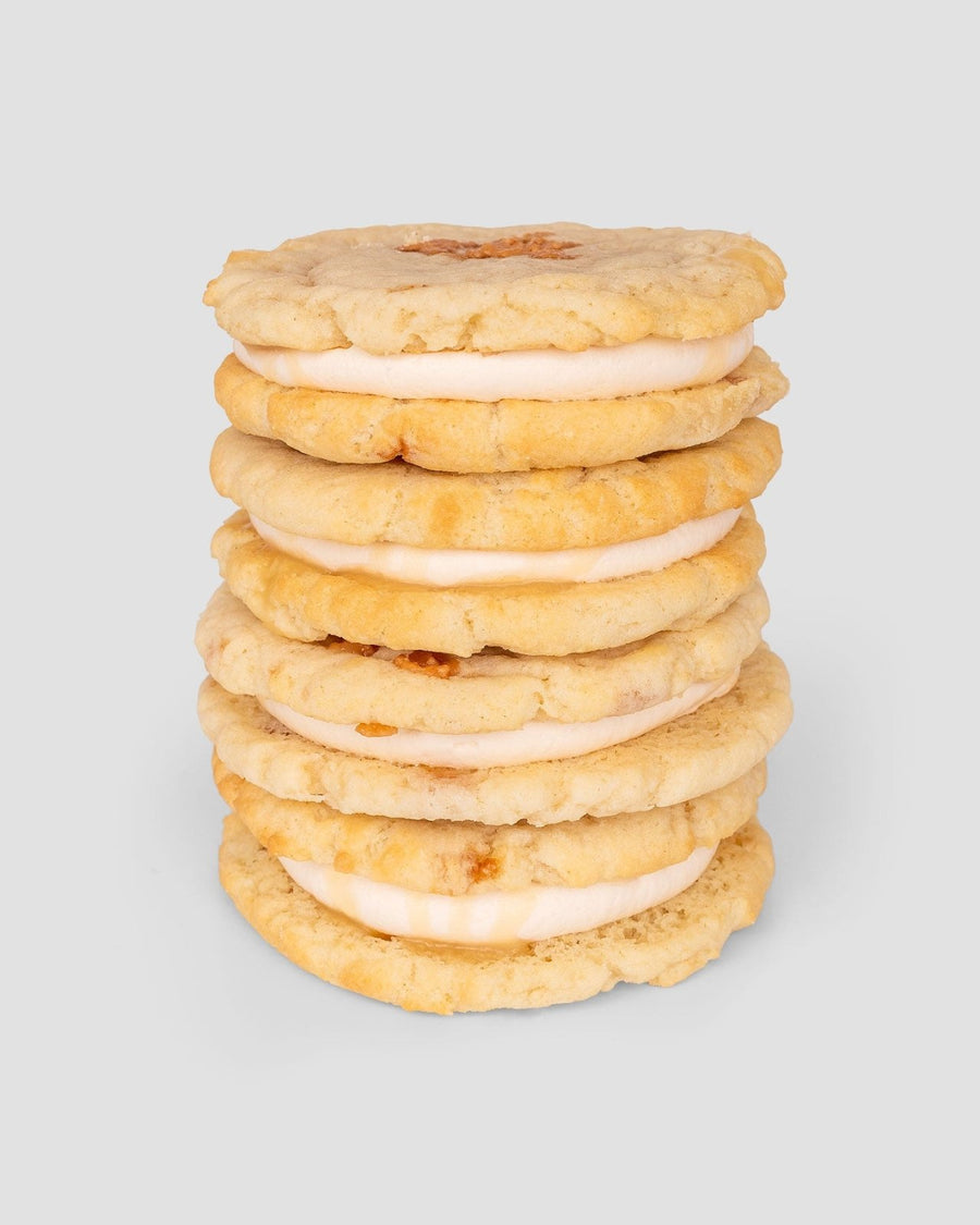 A stack of six Jenna Rae Cakes Regular Cookie Sandwiches, featuring cream filling between two golden cookies, set against a plain light gray background.