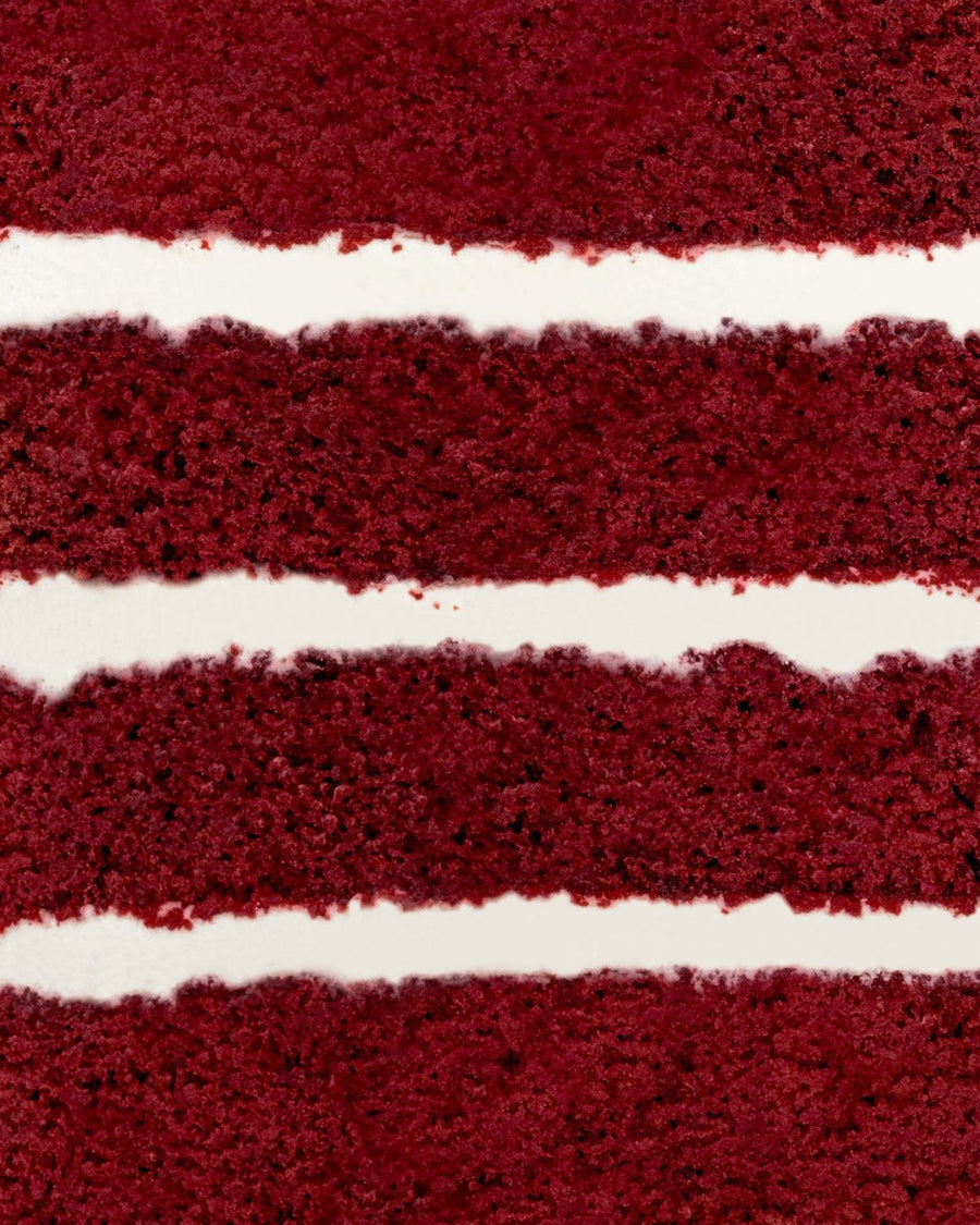 Close-up of Jenna Rae Cakes Red Velvet Cake, highlighting its moist, red-brown layers and thick, smooth cream cheese frosting in between.